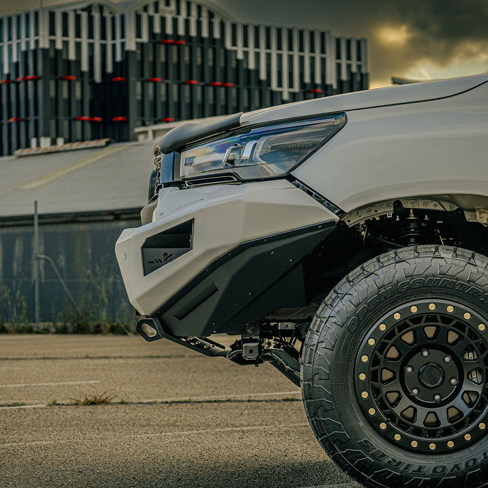 Close-up of a white off-road vehicle with large black tires in an urban setting.